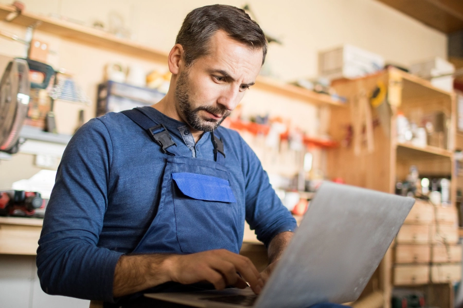 Man typing on laptop in workshop