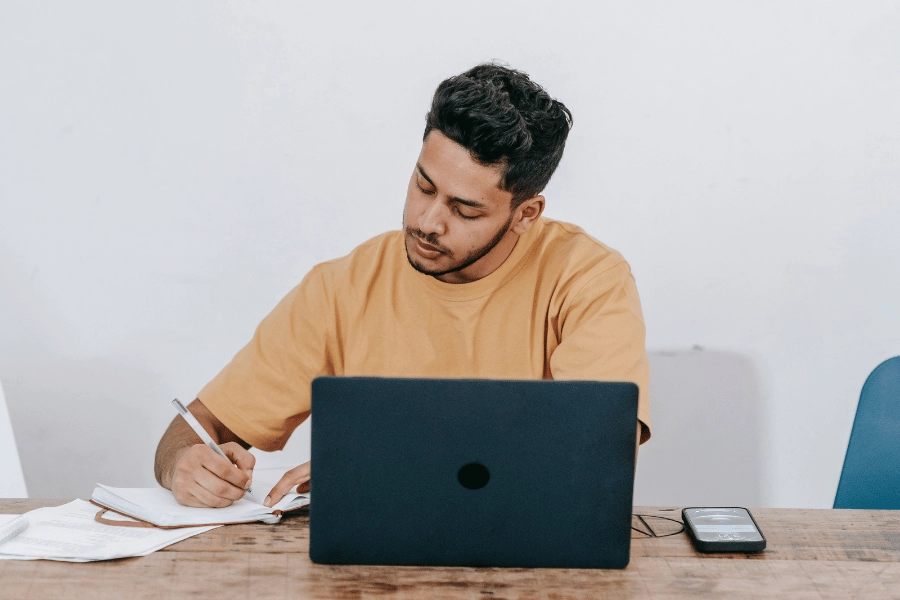 Man on laptop taking notes