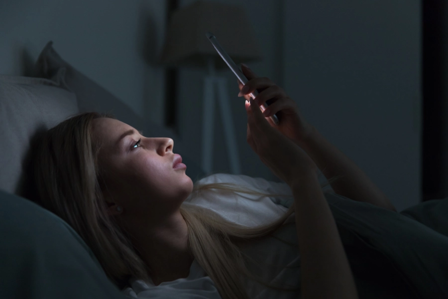 Woman in bed looking at phone