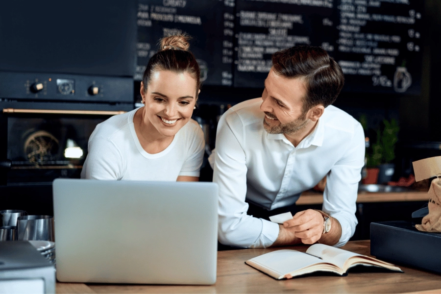 Coffee shop owners looking at laptop